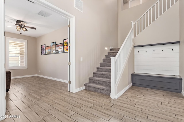 stairs featuring a ceiling fan, wood finish floors, and baseboards