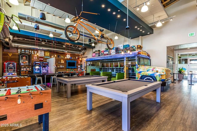 game room featuring billiards table, wood finished floors, a towering ceiling, and rail lighting