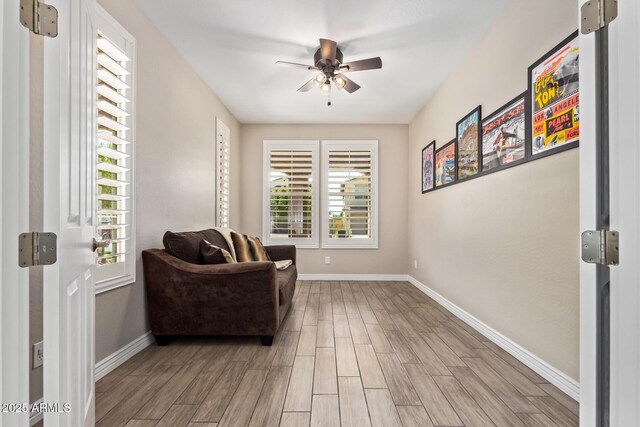 sitting room featuring baseboards, ceiling fan, and light wood-style flooring
