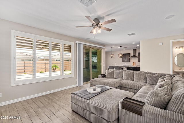 living area with baseboards, ceiling fan, and light wood-style floors