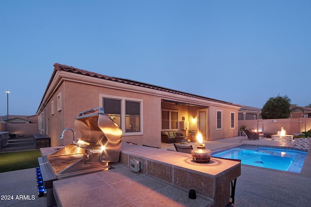 pool at dusk featuring a fire pit, area for grilling, and a patio area