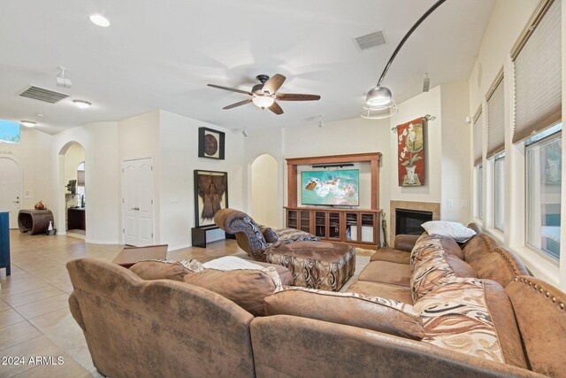 living room with a tile fireplace, ceiling fan, plenty of natural light, and light tile patterned flooring