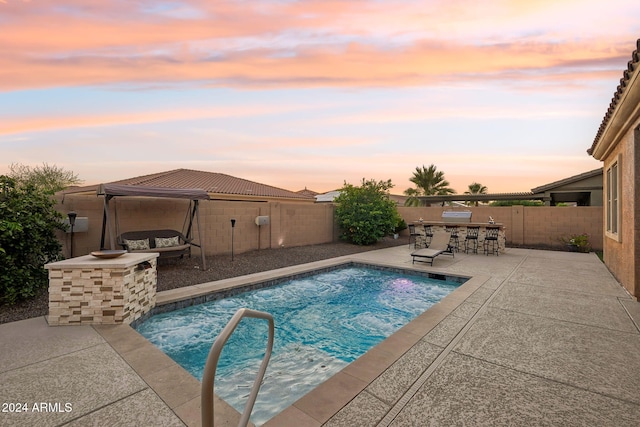 pool at dusk featuring a patio area