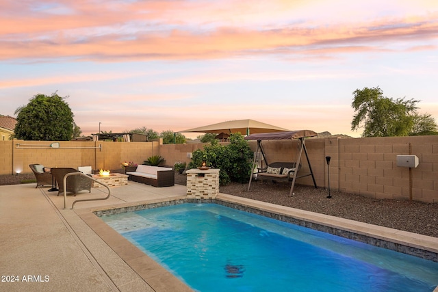 pool at dusk with a fire pit and a patio area