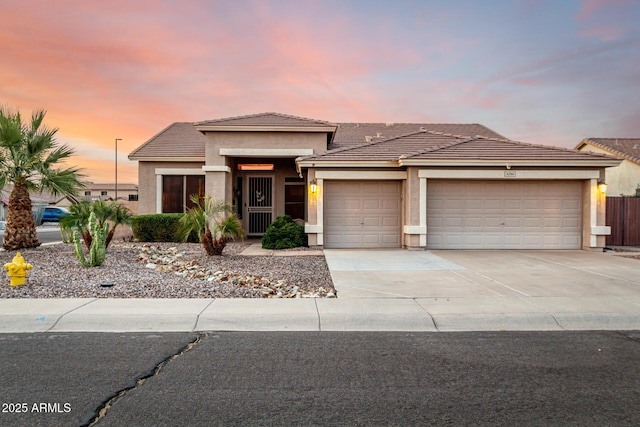 prairie-style home with a garage, stucco siding, driveway, a tile roof, and fence