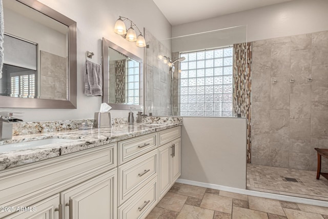 bathroom with walk in shower, double vanity, stone finish floors, and baseboards