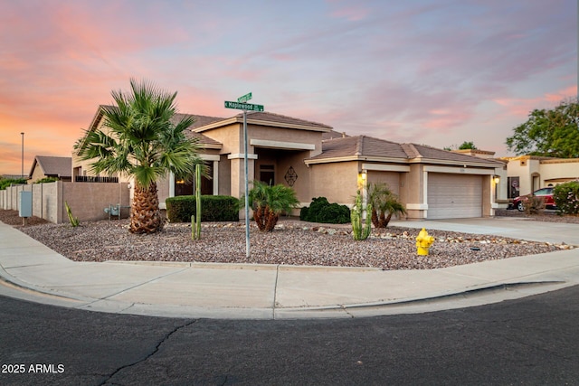 view of front facade with stucco siding, an attached garage, concrete driveway, fence, and a tile roof
