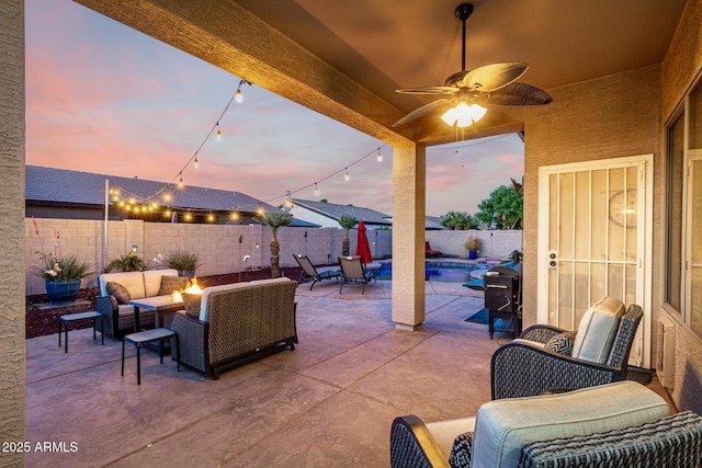 patio terrace at dusk featuring an outdoor living space with a fire pit, a fenced backyard, and a ceiling fan