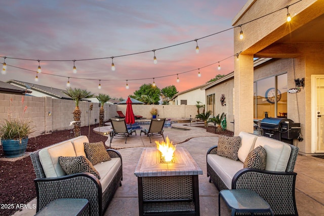 patio terrace at dusk with an outdoor living space with a fire pit, grilling area, and a fenced backyard