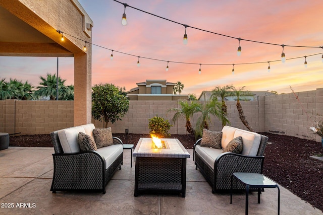 patio terrace at dusk with an outdoor living space with a fire pit and a fenced backyard
