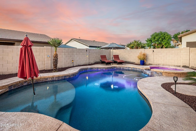 view of swimming pool with a fenced backyard and a pool with connected hot tub