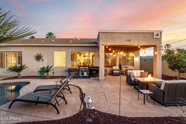 back of property at dusk with an outdoor living space with a fire pit, stucco siding, a patio, an outdoor pool, and fence