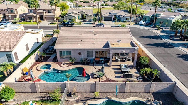 view of swimming pool with a residential view, a fenced backyard, a pool with connected hot tub, and a patio area