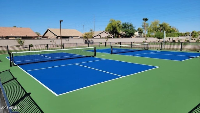 view of tennis court with community basketball court and fence