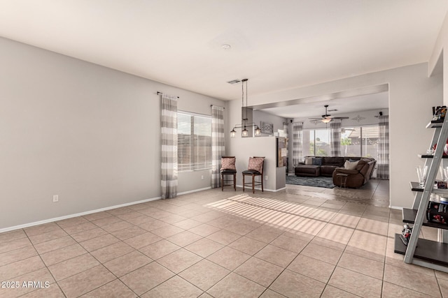 living area featuring healthy amount of natural light, ceiling fan, light tile patterned floors, and baseboards