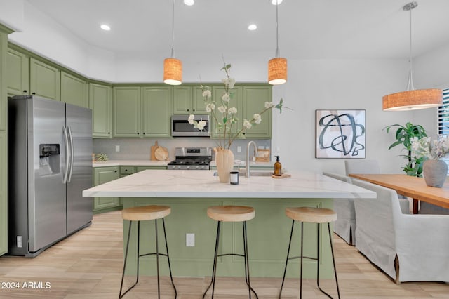 kitchen featuring a kitchen island with sink, light hardwood / wood-style floors, and stainless steel appliances