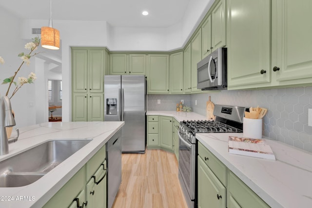 kitchen featuring sink, green cabinetry, decorative light fixtures, and appliances with stainless steel finishes