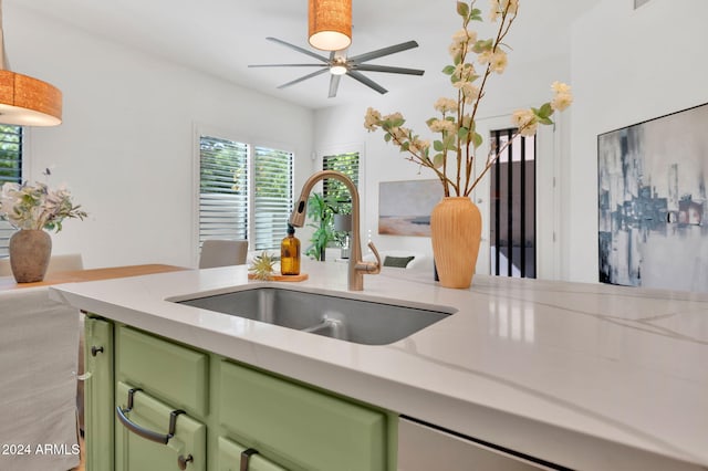 kitchen with light stone countertops, ceiling fan, sink, and green cabinetry