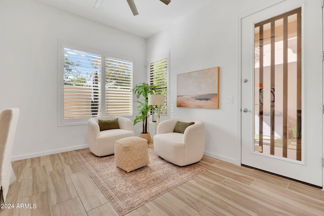 living area with ceiling fan and light hardwood / wood-style flooring