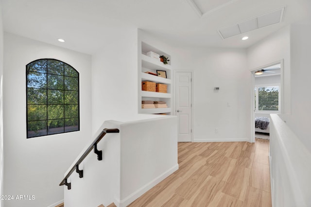 corridor featuring a wealth of natural light, built in features, and light hardwood / wood-style floors