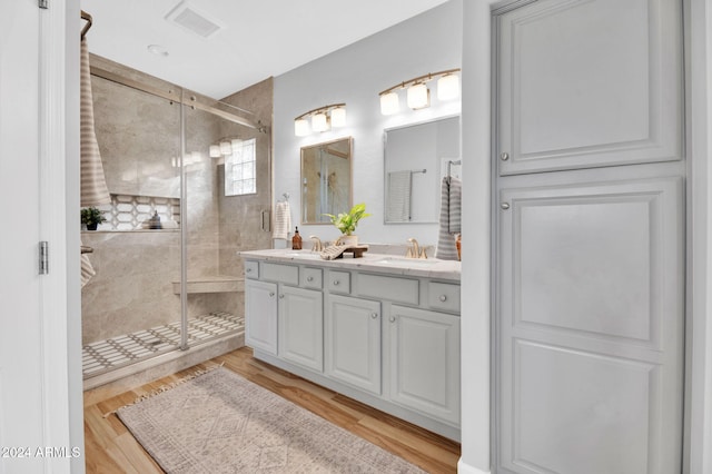 bathroom with wood-type flooring, vanity, and an enclosed shower