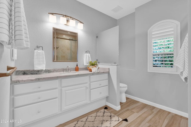 bathroom featuring wood-type flooring, vanity, toilet, and an enclosed shower