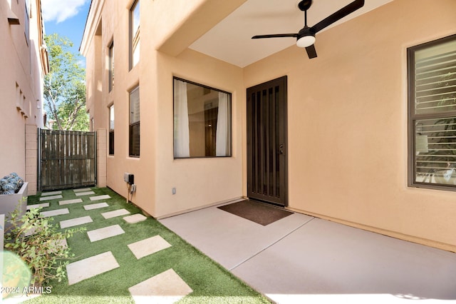 view of exterior entry featuring ceiling fan and a patio area