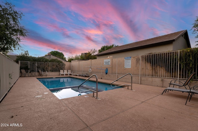 pool at dusk with a patio area