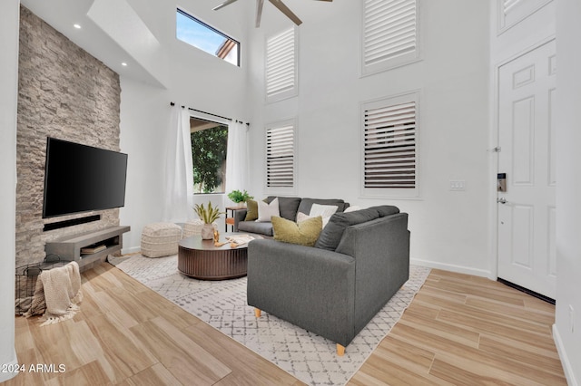 living room with ceiling fan, hardwood / wood-style flooring, a high ceiling, and a healthy amount of sunlight