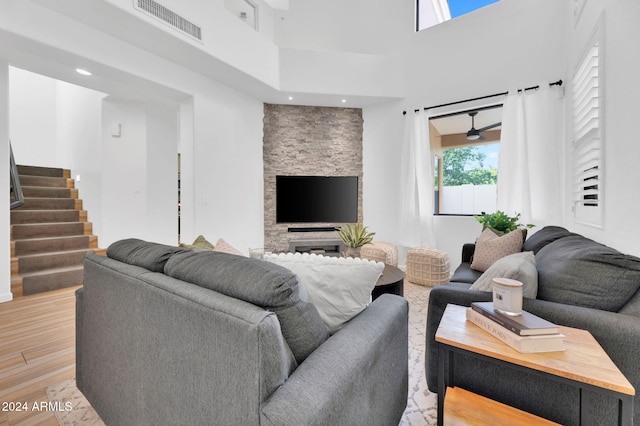 living room featuring a high ceiling, ceiling fan, and light hardwood / wood-style flooring