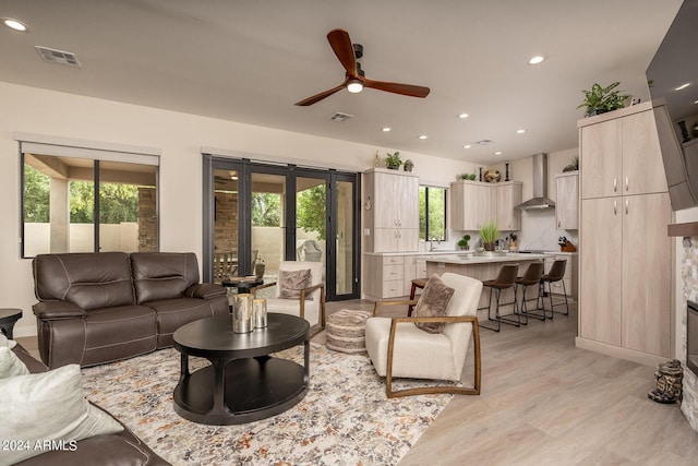 living room featuring ceiling fan, a wealth of natural light, and light hardwood / wood-style flooring