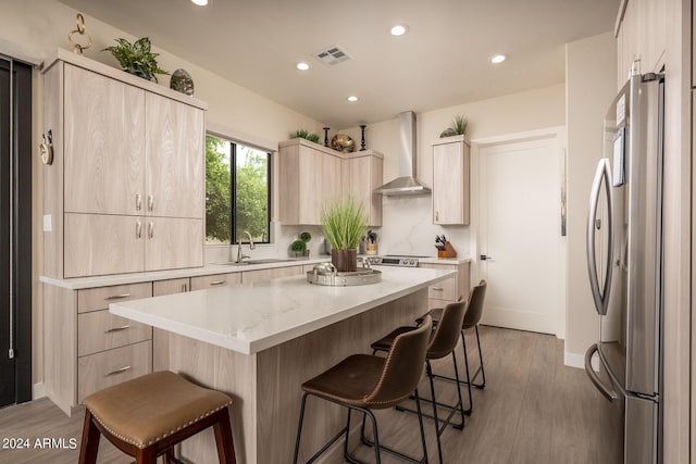 kitchen with a center island, a kitchen bar, dark wood-type flooring, wall chimney range hood, and stainless steel fridge