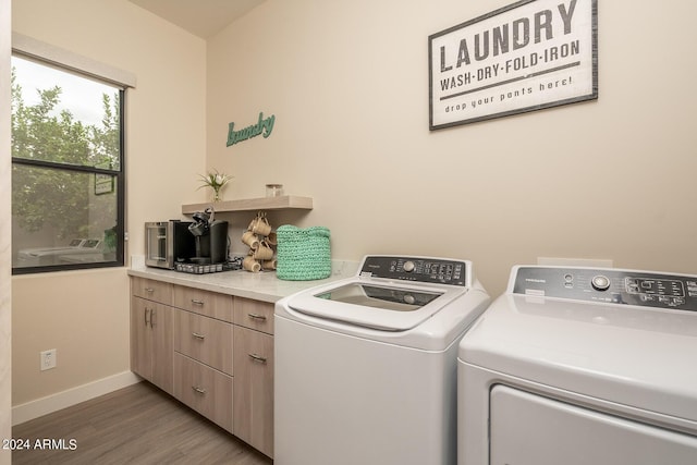 washroom with hardwood / wood-style flooring, cabinets, and washing machine and dryer