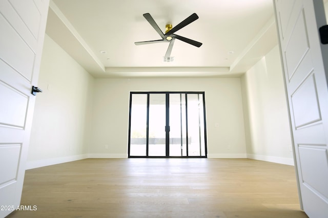 spare room with light hardwood / wood-style flooring, ceiling fan, and a tray ceiling