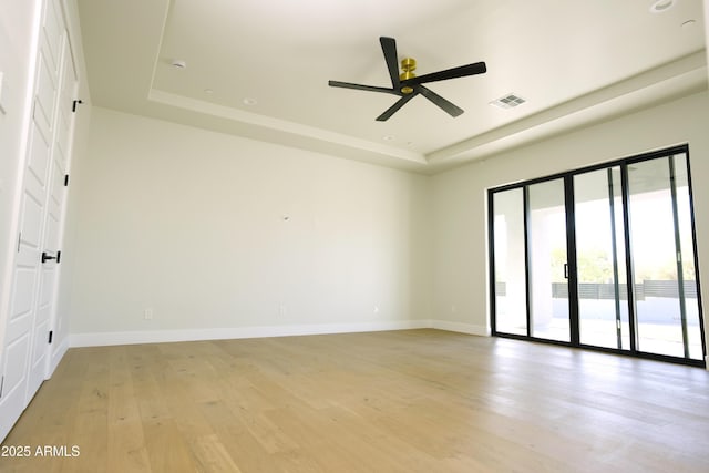 unfurnished room with ceiling fan, a raised ceiling, and light hardwood / wood-style flooring