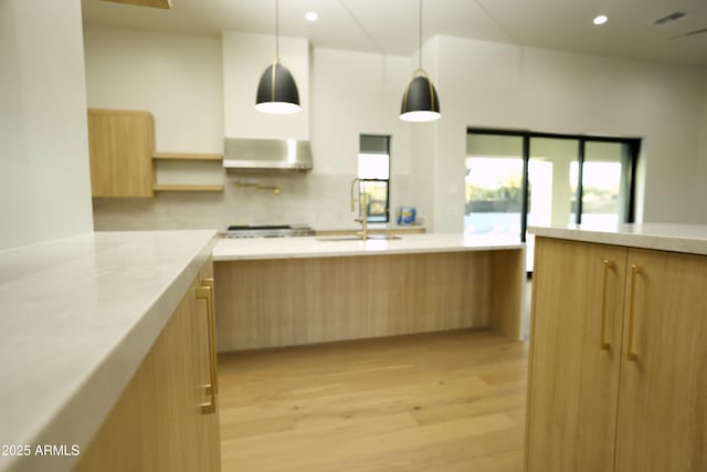 kitchen featuring sink, hanging light fixtures, range hood, light brown cabinetry, and light wood-type flooring