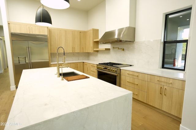 kitchen featuring sink, hanging light fixtures, high end appliances, light hardwood / wood-style floors, and light brown cabinets