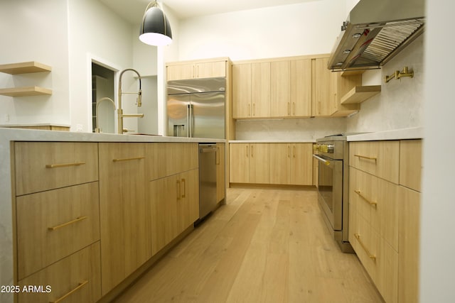 kitchen with sink, hanging light fixtures, high quality appliances, light hardwood / wood-style floors, and light brown cabinets