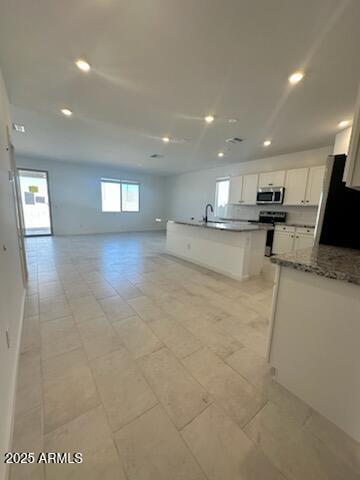 25336 W Bowker St, Buckeye, AZ 85326 - kitchen with open floor plan, appliances with stainless steel finishes, a kitchen island with sink, and white cabinets