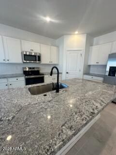 25336 W Bowker St, Buckeye, AZ 85326 - kitchen featuring light stone counters, a sink, white cabinetry, and stainless steel appliances