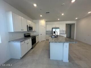 25336 W Bowker St, Buckeye, AZ 85326 - kitchen featuring a center island with sink, a sink, white cabinetry, and stainless steel appliances