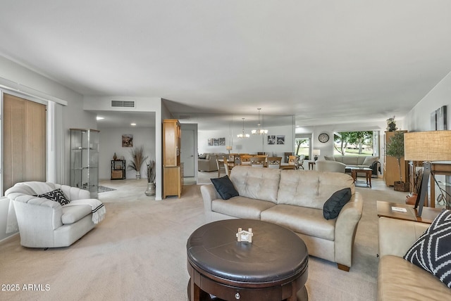 living area with visible vents, light carpet, and an inviting chandelier