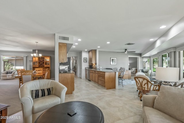 living area with ceiling fan with notable chandelier, recessed lighting, and visible vents