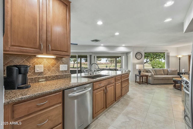 kitchen with a sink, brown cabinets, tasteful backsplash, and appliances with stainless steel finishes