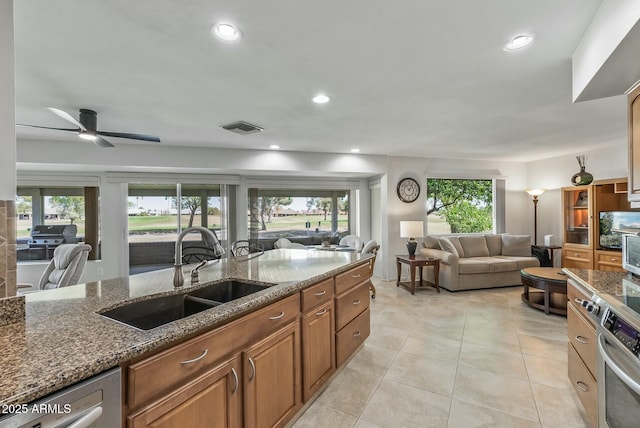 kitchen featuring visible vents, a sink, dark stone countertops, open floor plan, and dishwasher