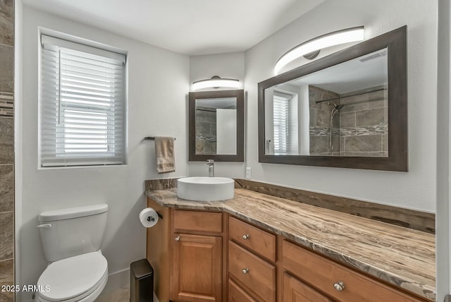 bathroom with a wealth of natural light, a tile shower, toilet, and vanity