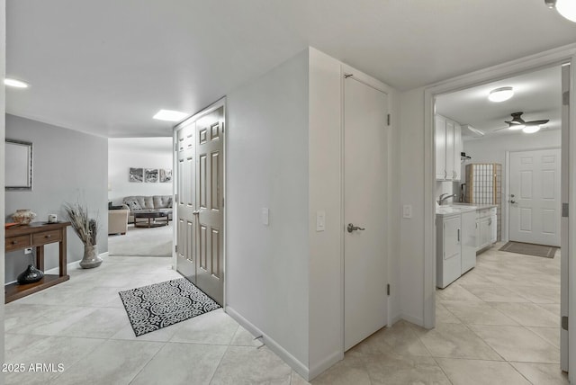 hallway with light tile patterned floors, baseboards, and independent washer and dryer