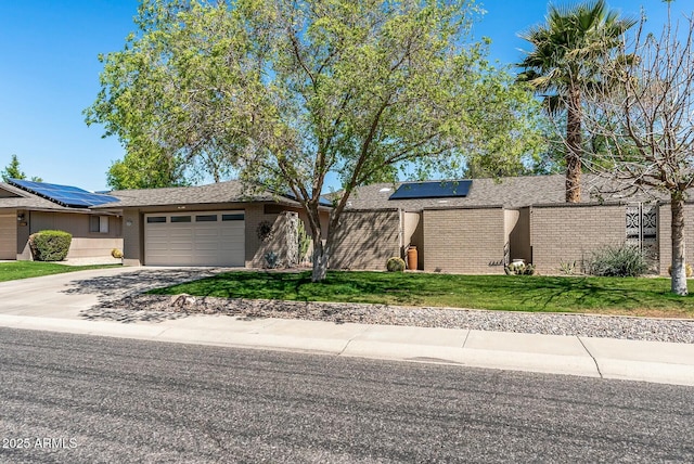 view of front facade featuring an attached garage, a front lawn, concrete driveway, brick siding, and roof mounted solar panels