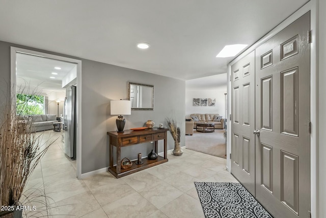 hall with a skylight and baseboards