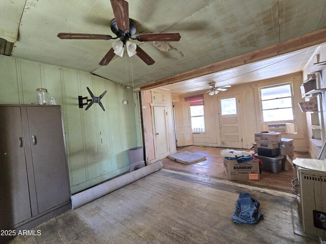 interior space featuring wood walls, wood-type flooring, a ceiling fan, and cooling unit